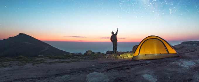Person camping in mountains under a starlit sky