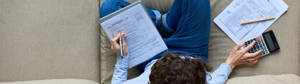 Person using a calculator with tax documents on the table